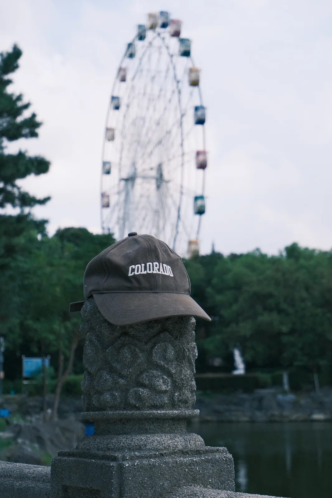 石雕、帽子与远处的摩天轮，组成一个安静的前后景。